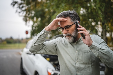 Worried man making a call after a car crash